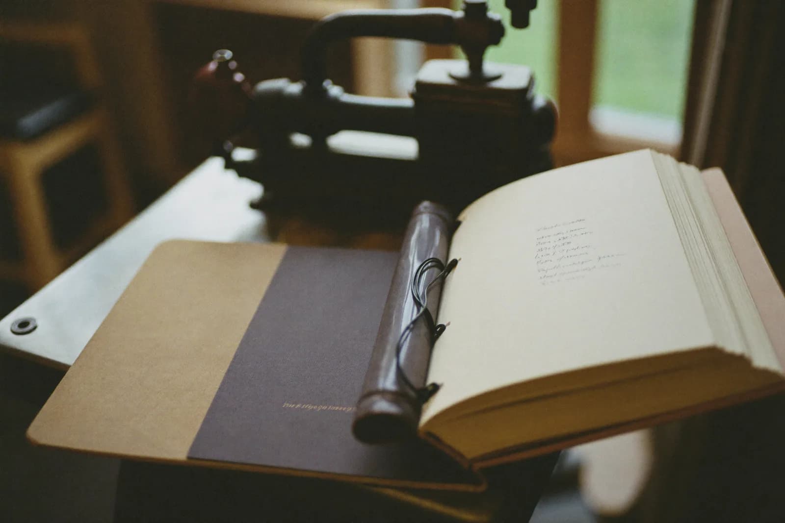 A bindery bench with a book in a finishing press, gold tooling laid out beside it and a wall of hand tools behind.