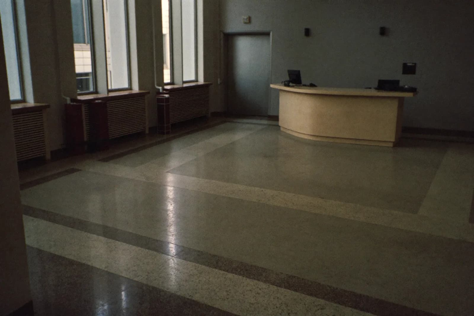 A quiet corporate lobby with a single empty reception desk and no one waiting.