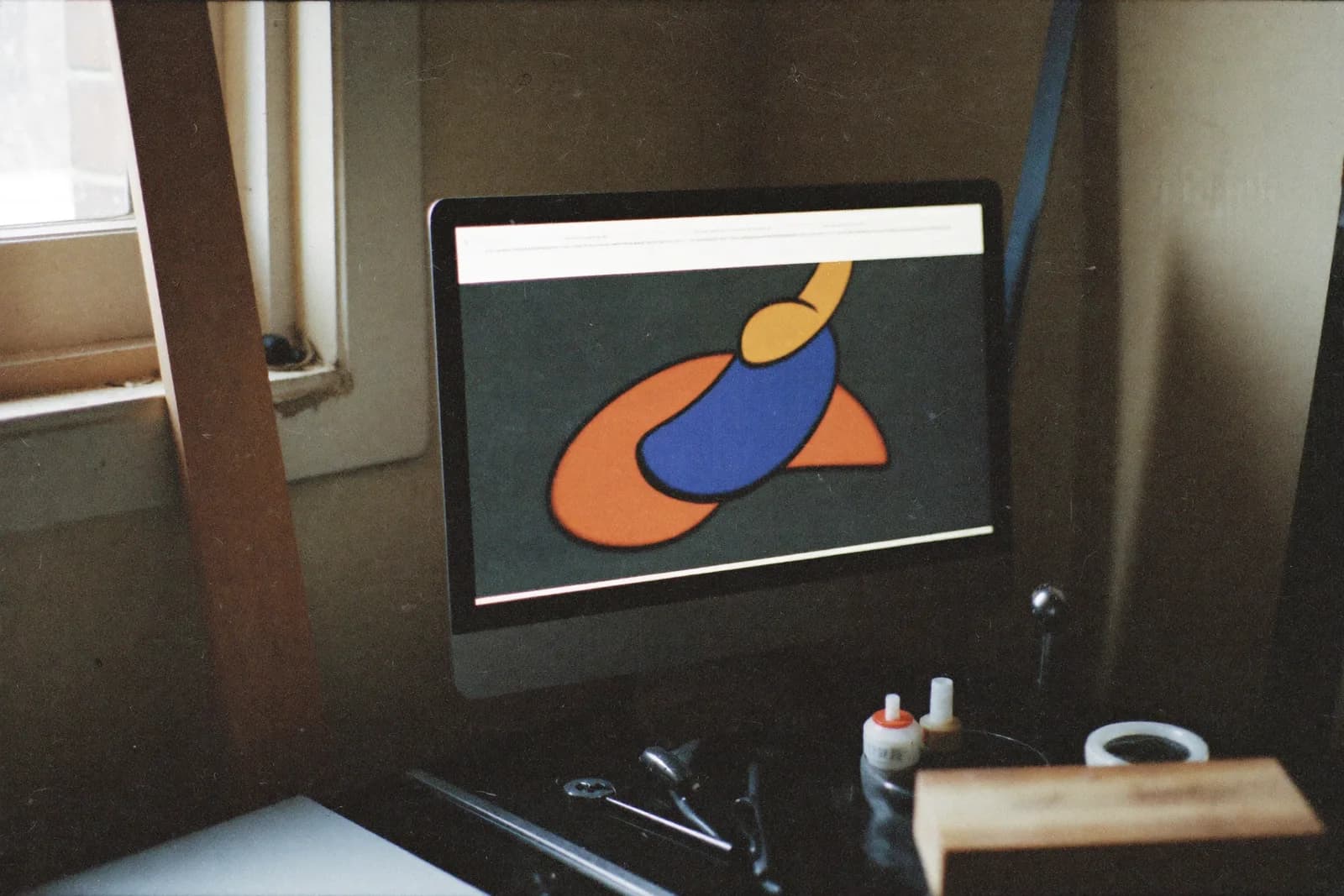 A dusty monitor mounted on a workshop wall showing a plain list of jobs, with tools on the bench below.