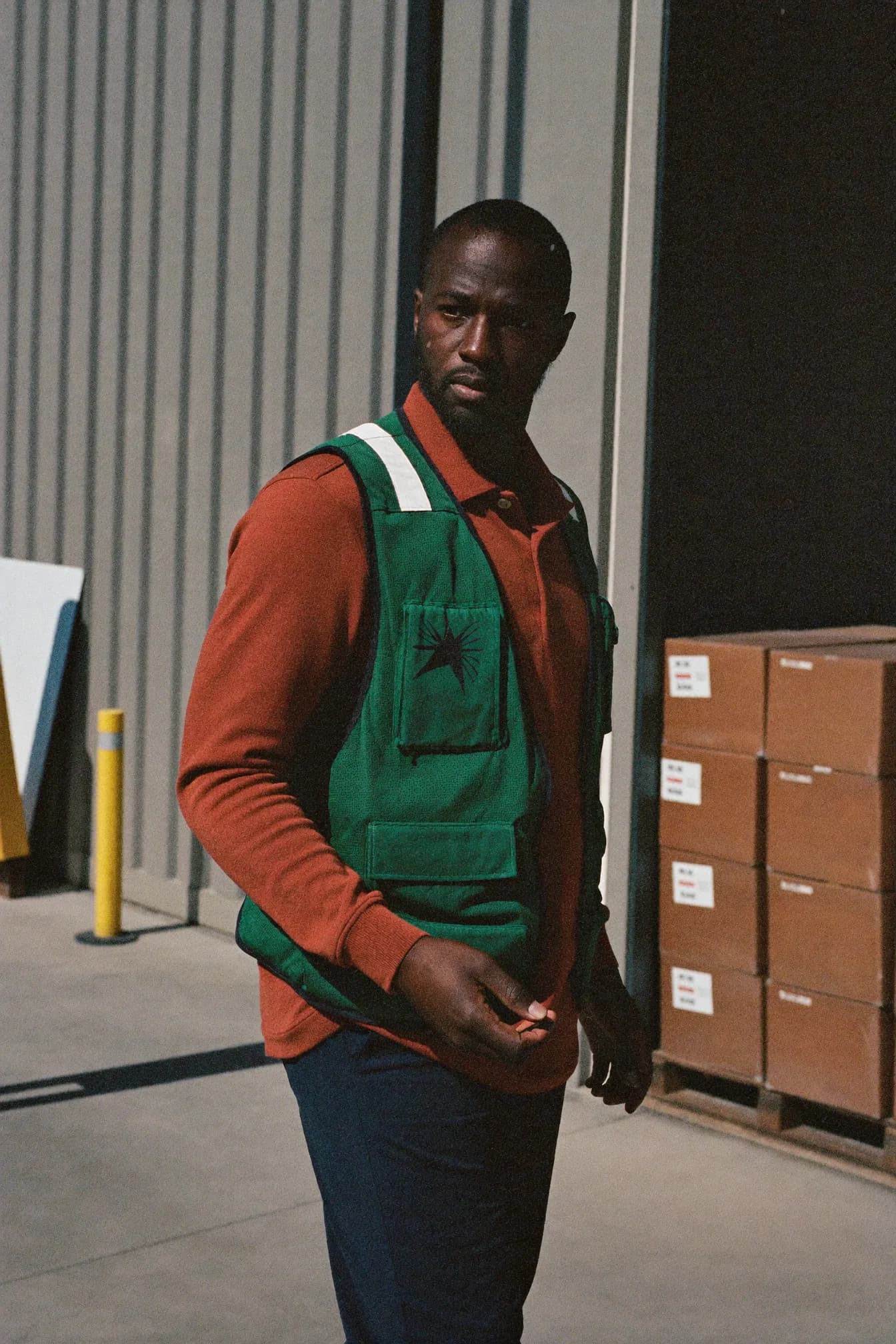 Daniel Kwame standing in a loading bay, arms folded, shipping containers behind him.
