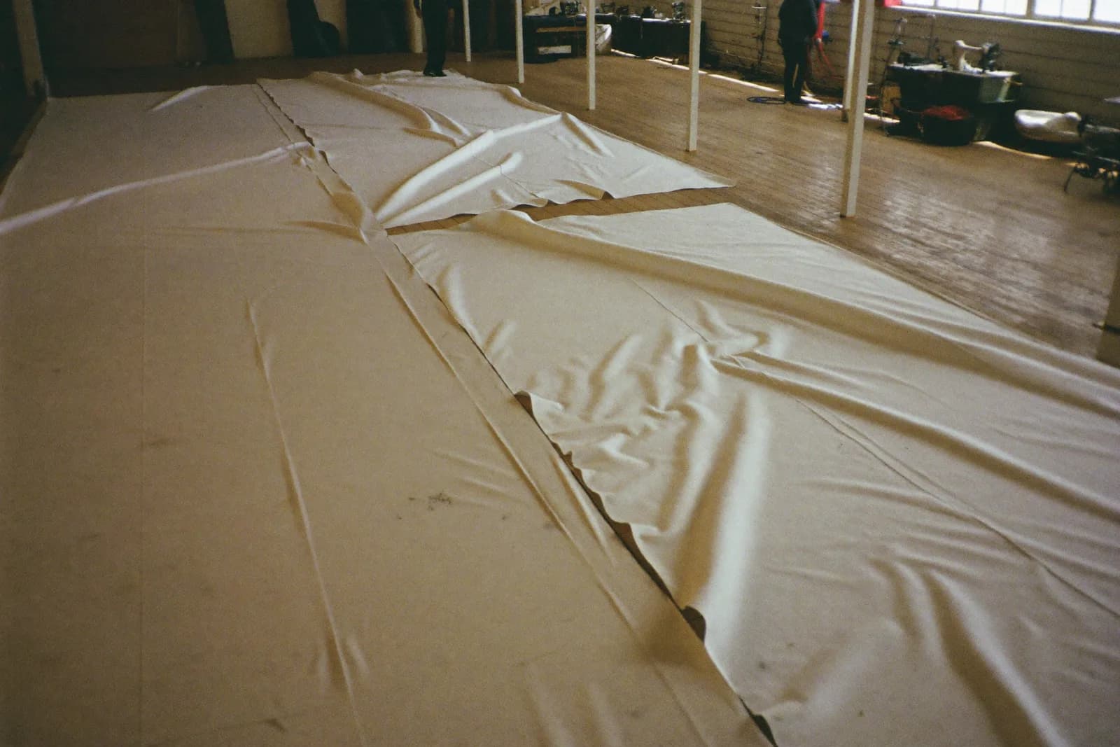 A sail loft with cut panels of white sailcloth spread across the floor.