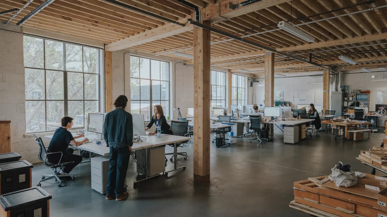 A small team gathered around a table in a converted warehouse workspace.