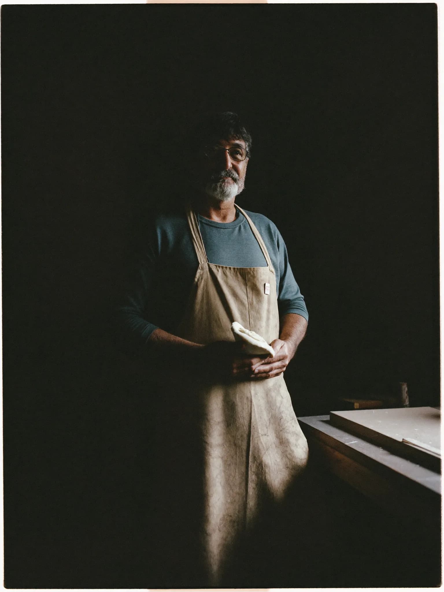 A founder standing in his workshop, holding a hand-shaped piece of work.